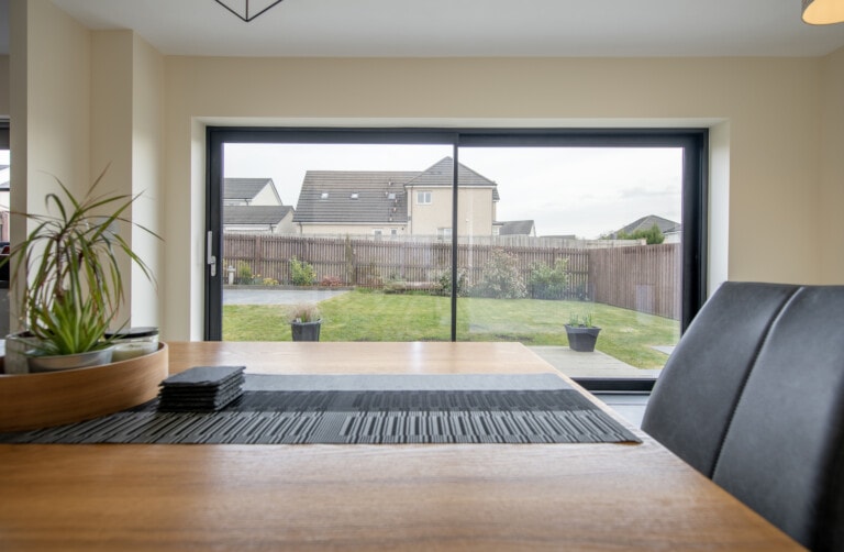 Black-framed twin-track sliding door opening from a dining room onto a rear garden